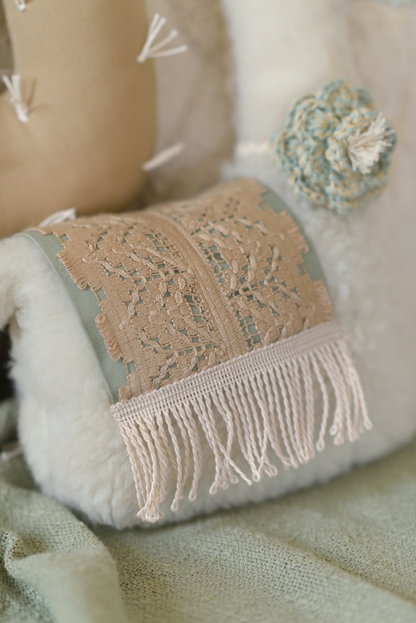 Close up of a sage saddle embellished with intricate tan lace and a sage crocheted flower on the llama's neck.