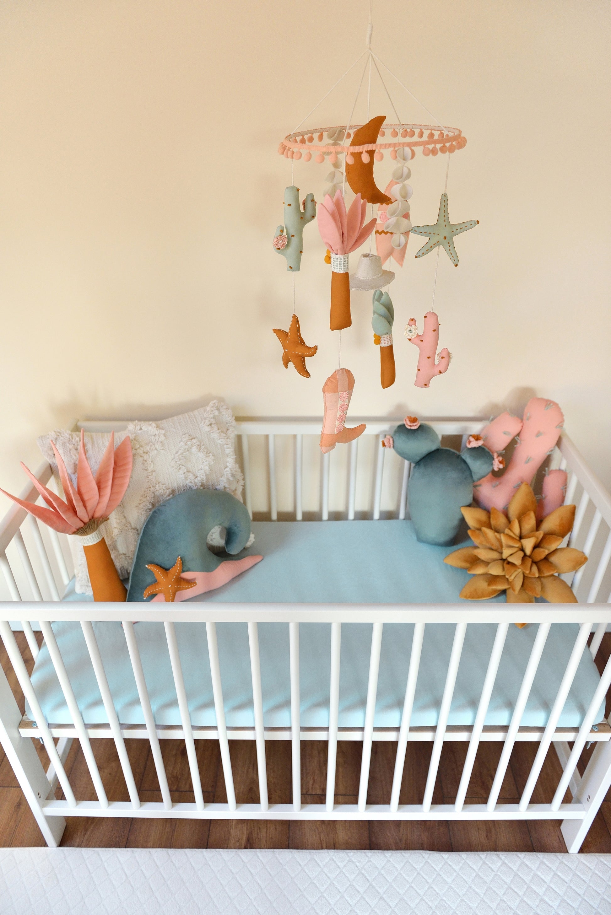 Baby crib with decorative pillows and a mobile hanging above.