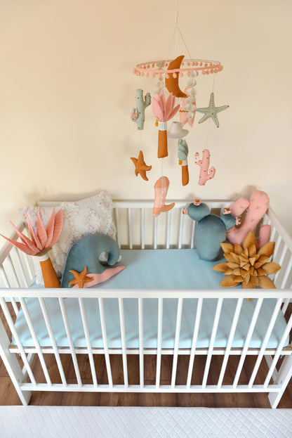 Baby crib with decorative pillows and a mobile hanging above.