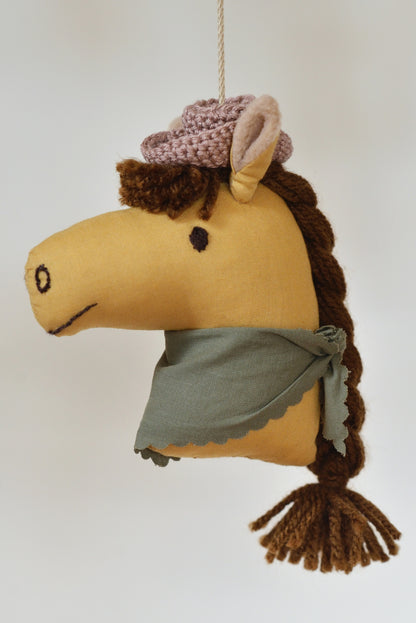 Closeup of horse head figure hanging off a rope with bandana and cowboy hat, long mane.