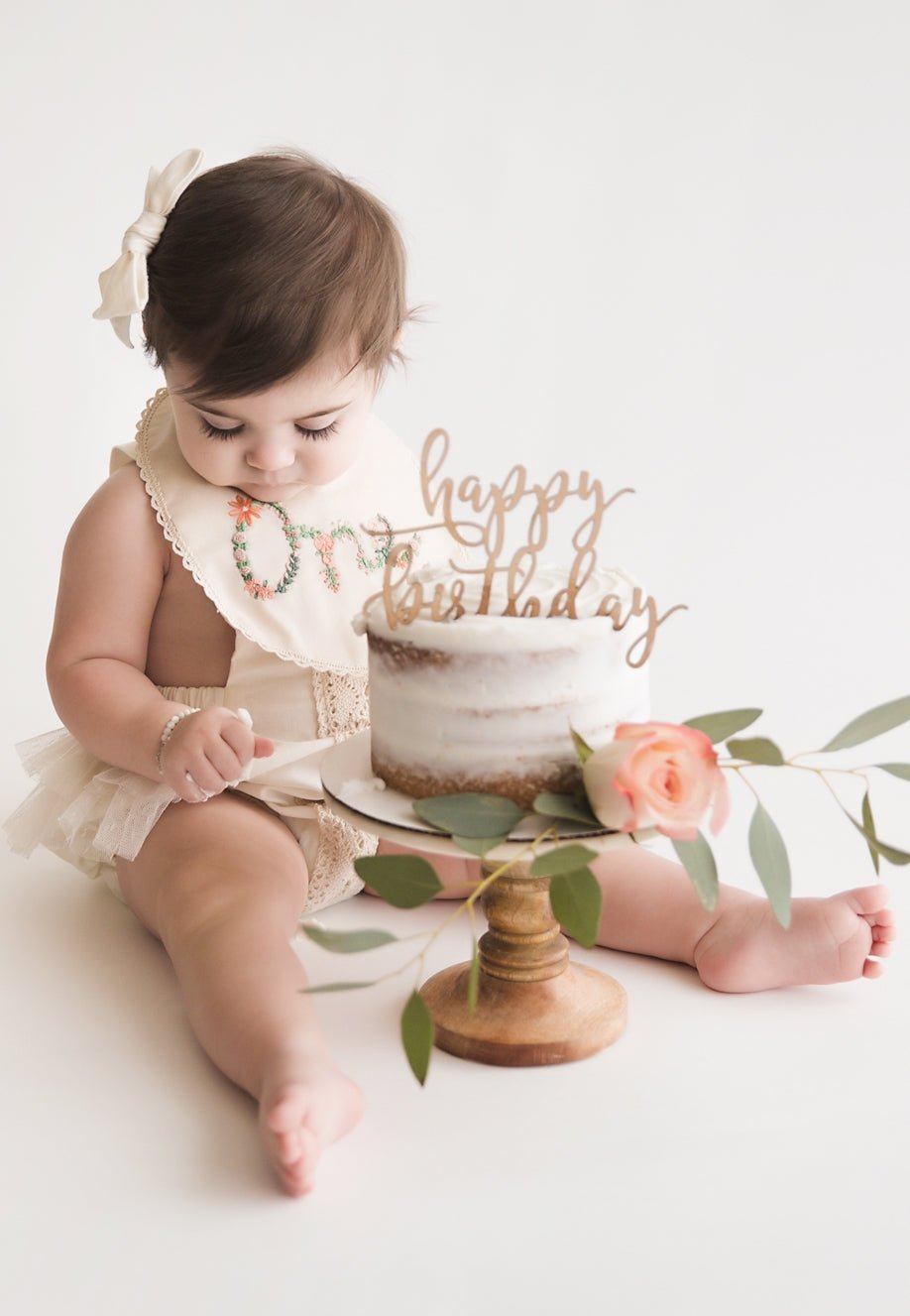 Baby girl with a birthday cake and 'happy birthday' topper 
