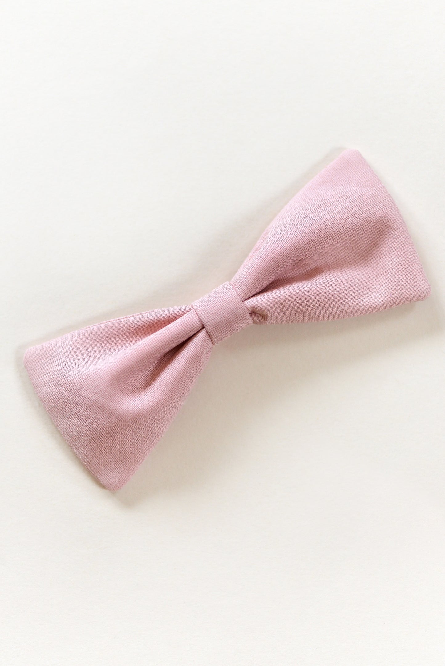 Handmade dusty pink bow on a light background.