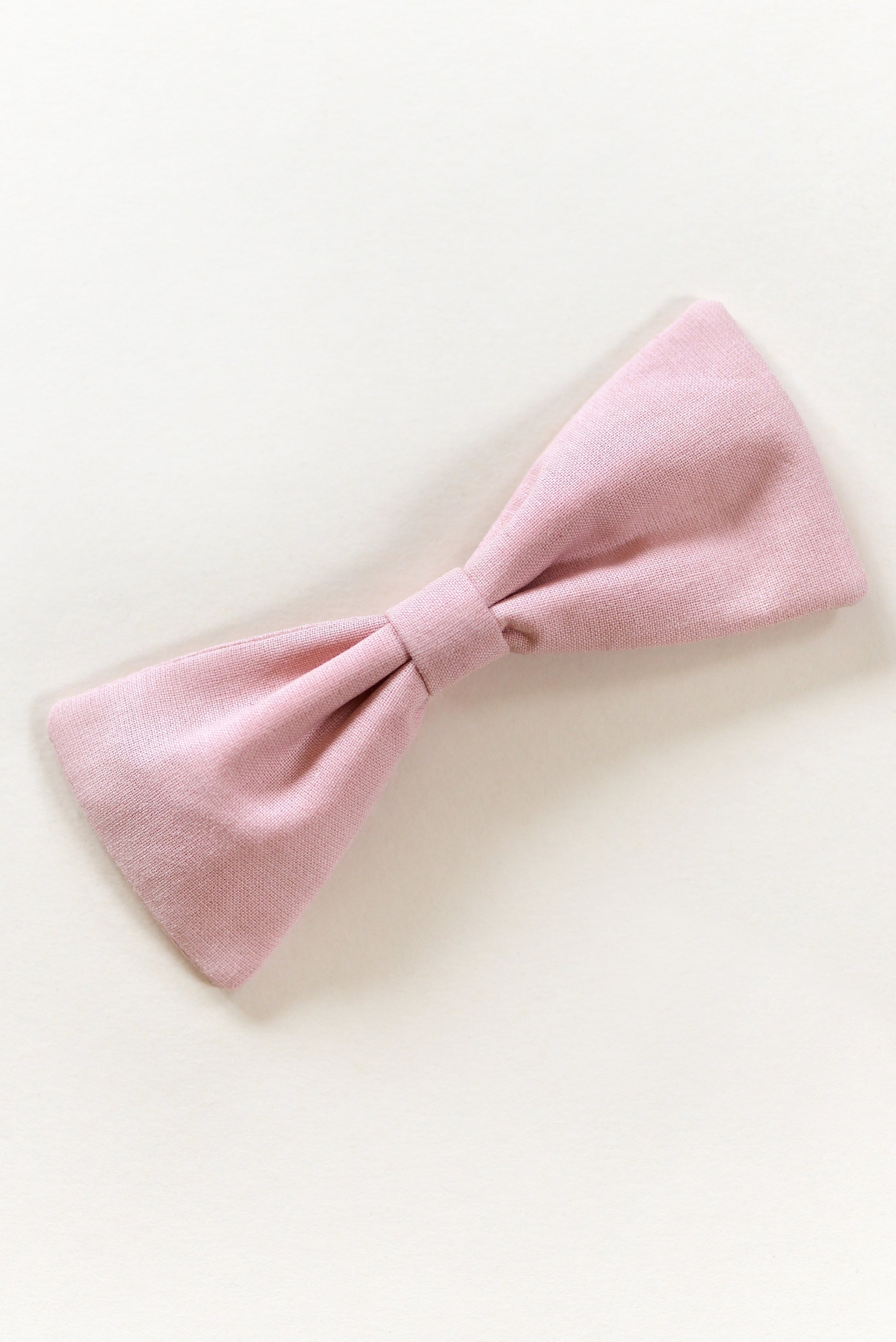 Handmade dusty pink bow on a light background.