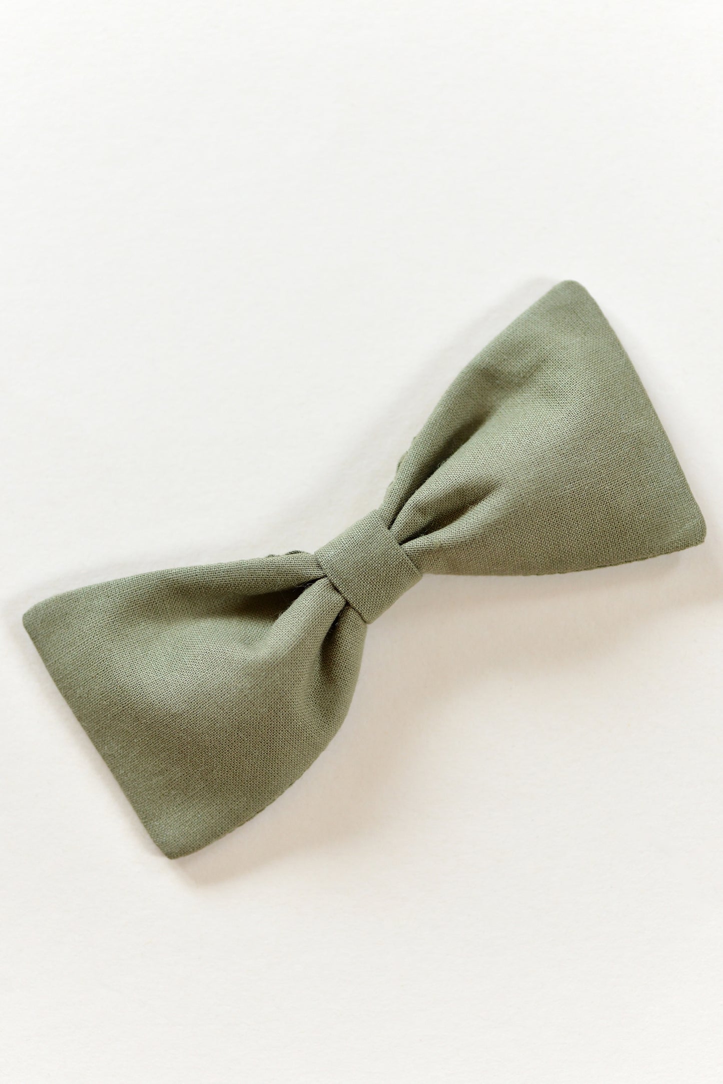 Handmade khaki green bow on a light background.