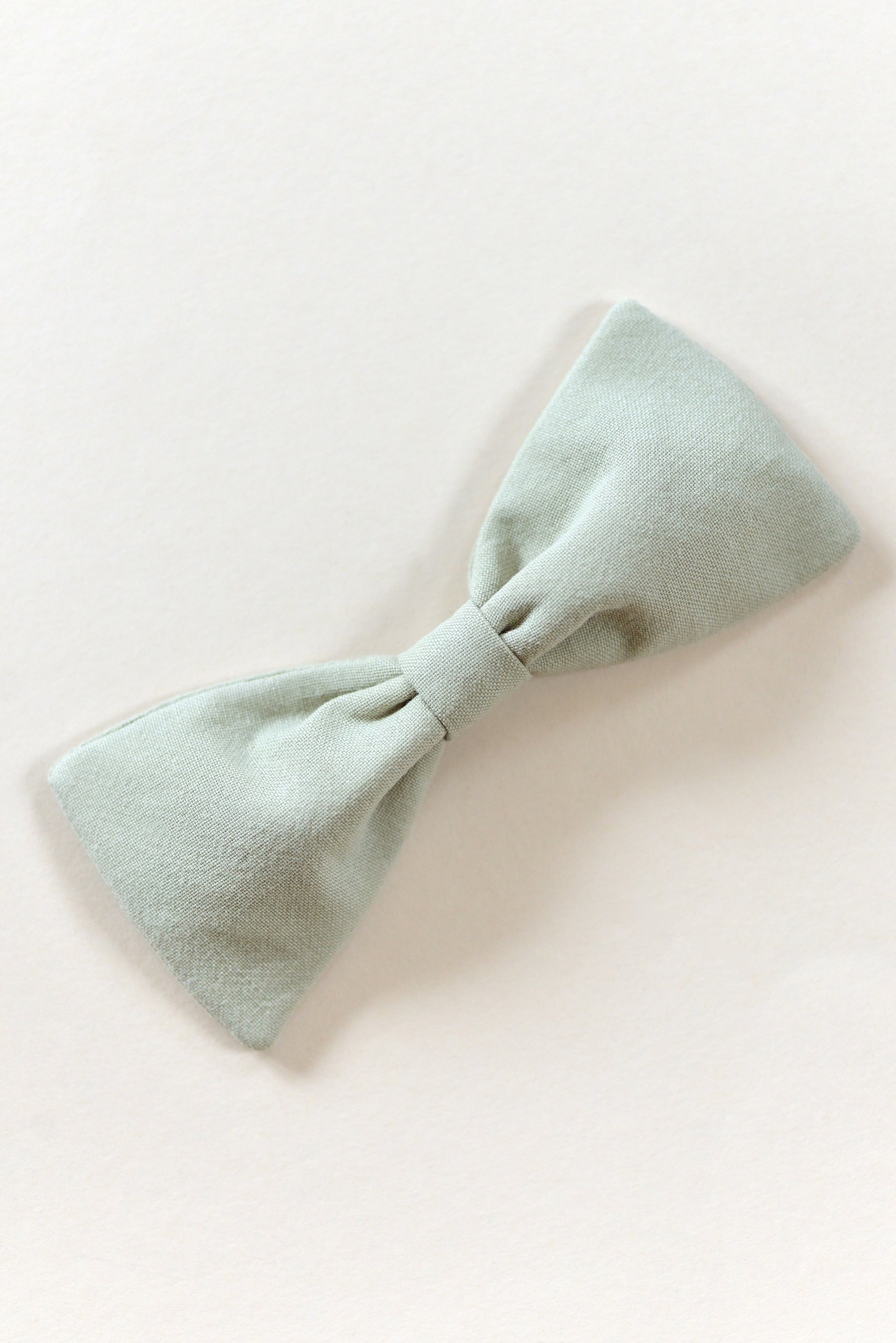 Handmade light sage bow on a light background.