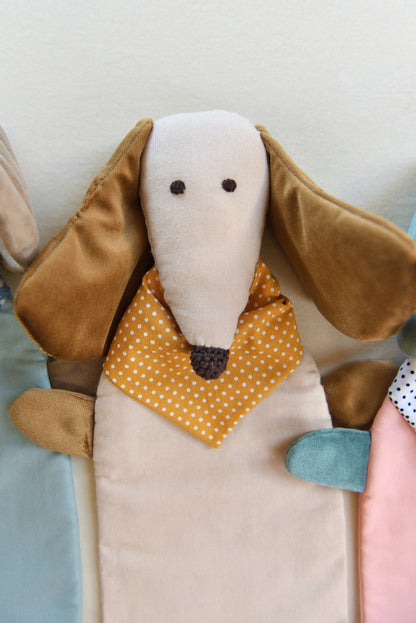 Dachshund Comforter up close with long ears and snouts featuring a cream body and brown coloured shiny ears. It wears an ochre bandana with white dots conveying a playful and cozy feel.