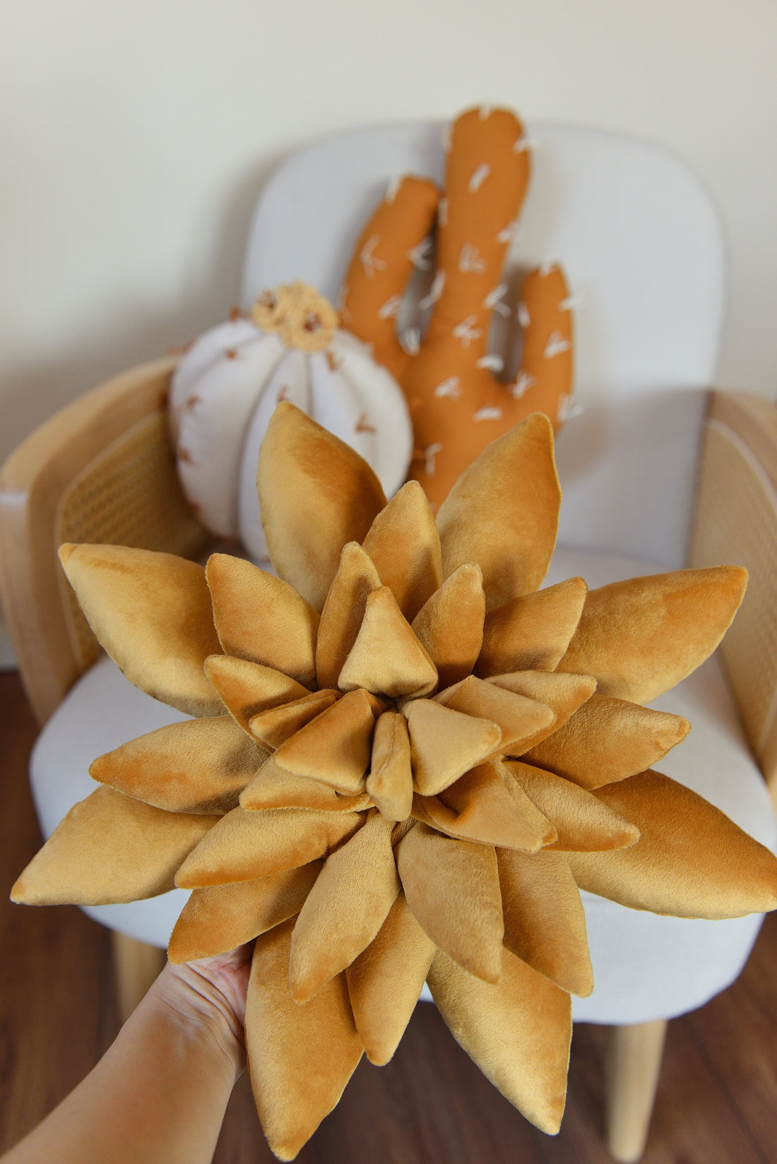 Hand holding gold succulent shaped decor pillow.