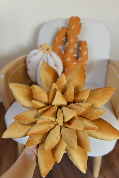 Hand holding gold succulent shaped decor pillow.