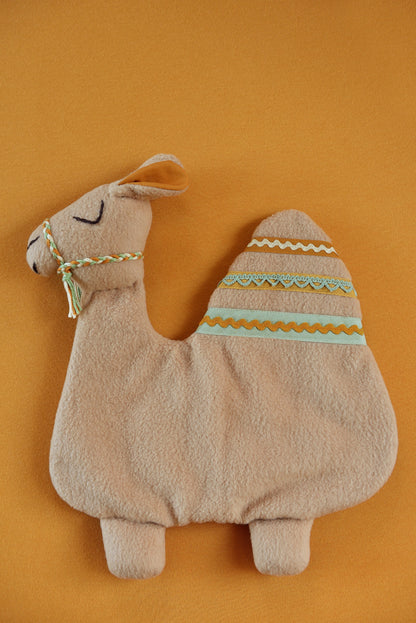 Handmade camel shaped baby comforter with tan body and green, tan and rust  lace details on a rust background.