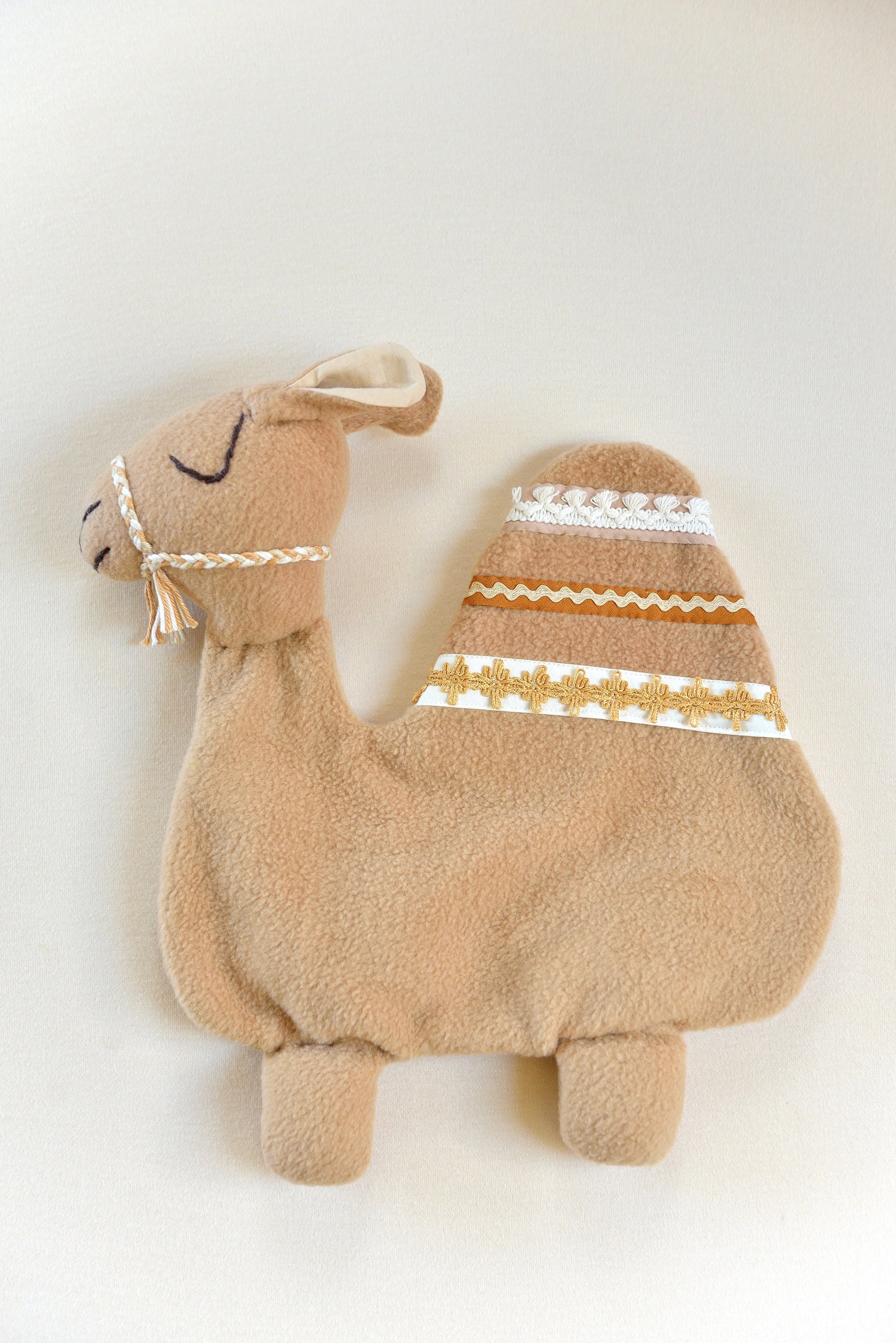 Handmade camel shaped baby comforter with tan body and white, mustard, tan and rust lace details on an ivory background.