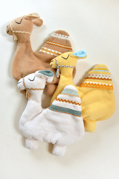 Selection of handmade camel shaped baby comforters with lace details on an ivory background in different colours: ivory, tan and yellow.