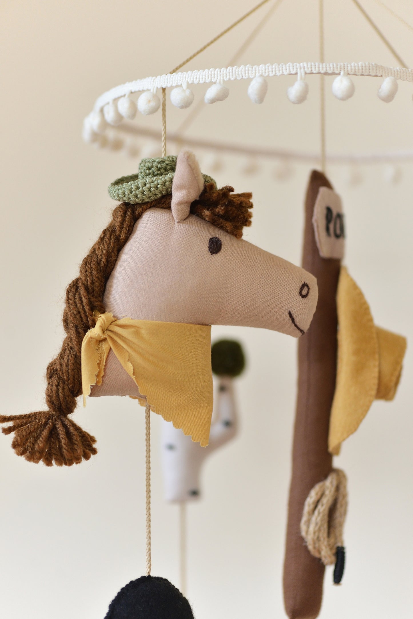 Handmade Wild West rodeo nursery mobile with cowboy boots, hats, horses, cacti, stars, and rodeo signpost in boho desert style.