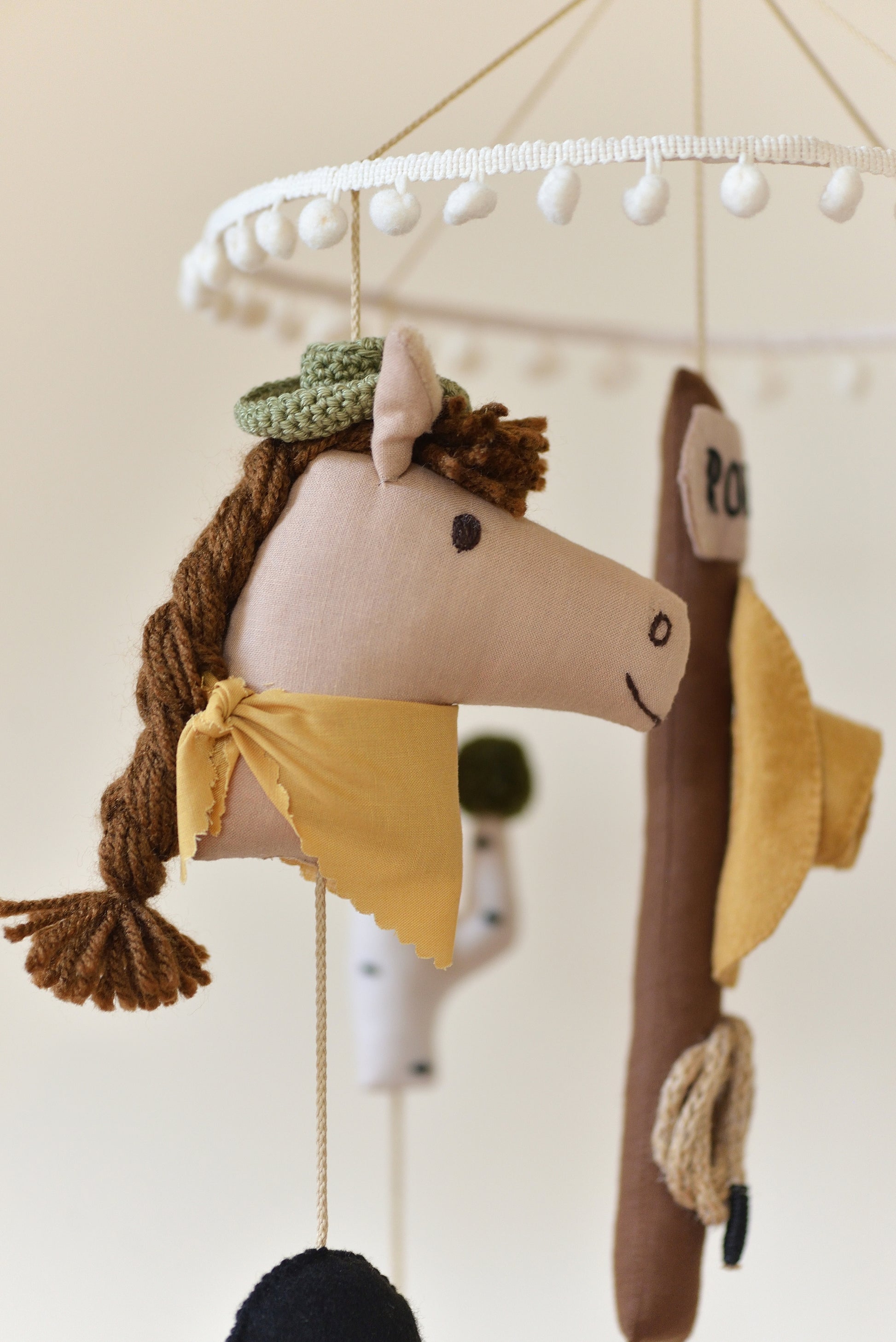 Handmade Wild West rodeo nursery mobile with cowboy boots, hats, horses, cacti, stars, and rodeo signpost in boho desert style.