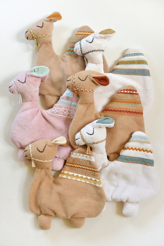 Selection of handmade camel shaped baby lovey with lace details on an ivory background in different colours: ivory, tan and blush pink.