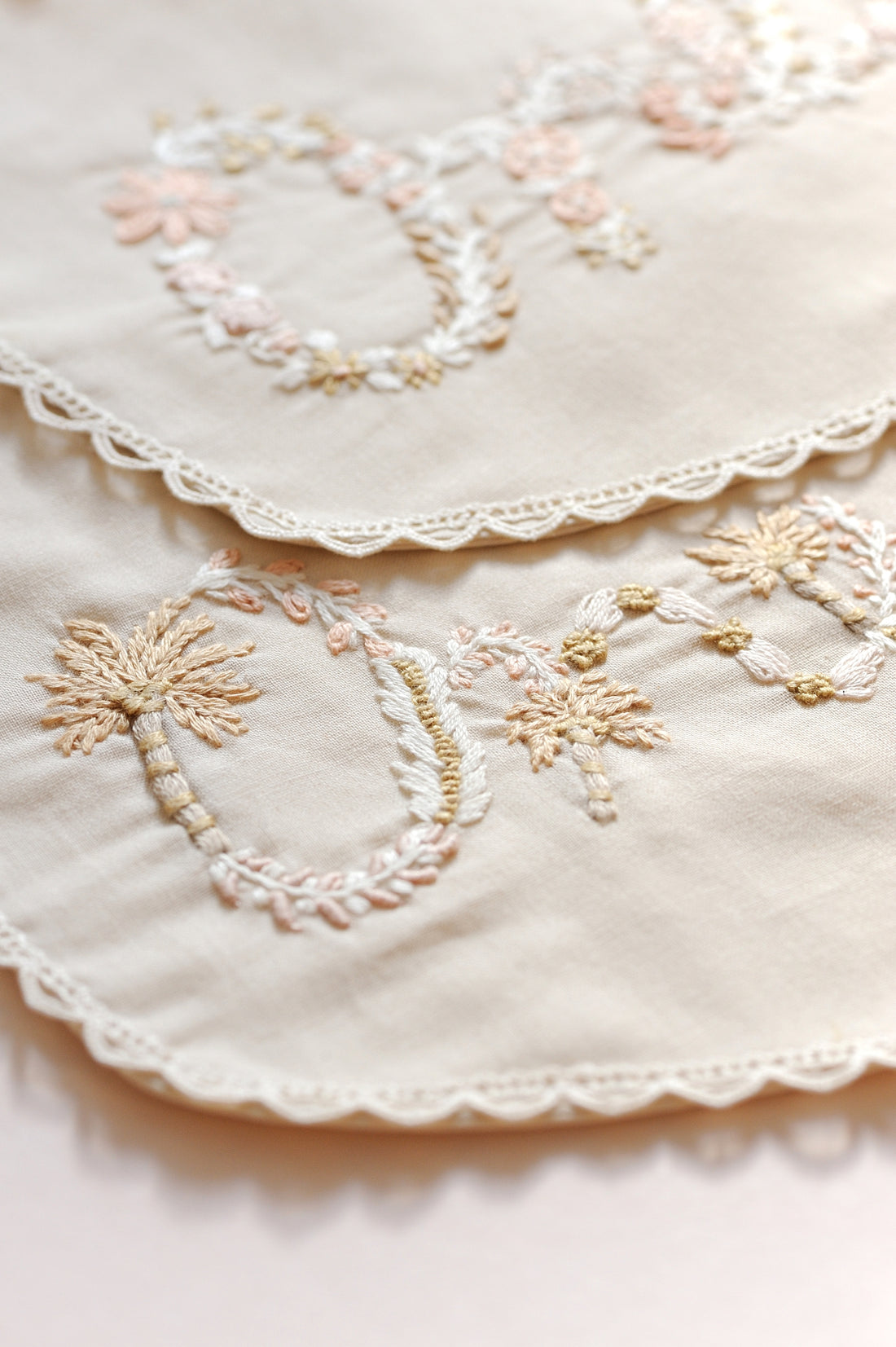 Close-up of embroidered milestone bib with floral patterns on a light background.