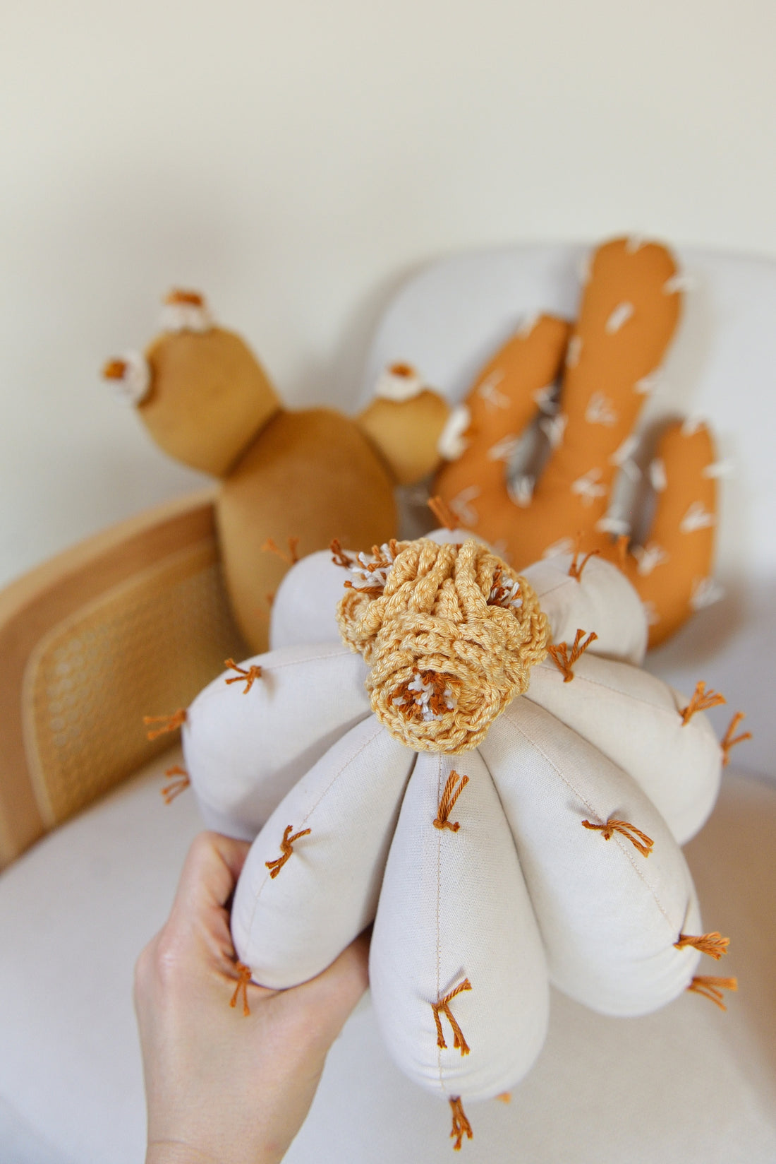 Hand holding ivory barrel cactus shaped decor pillow.
