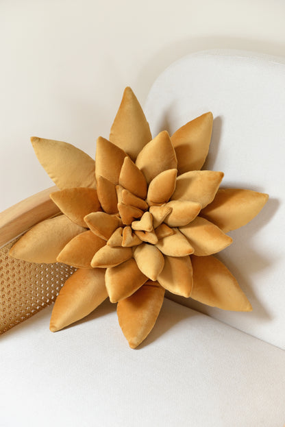 Large succulent shaped velvet decor pillow in golden yellow colour placed on an ivory rattan armchair.