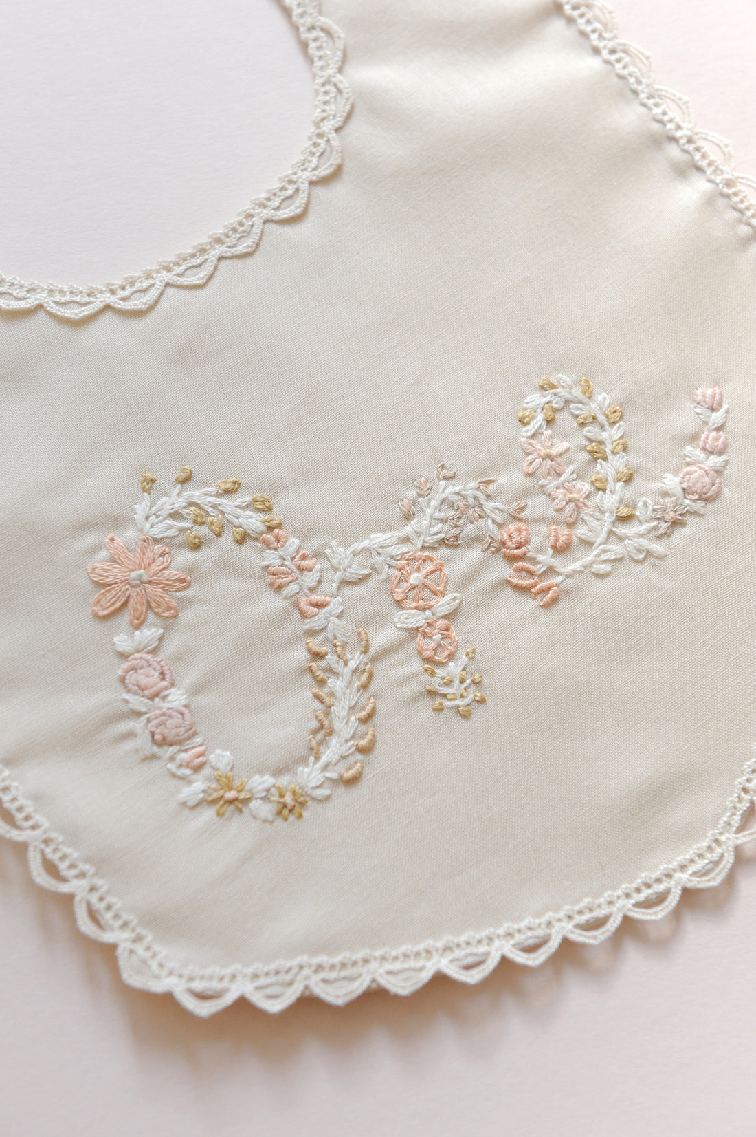 Embroidered ONE bib with floral patterns on a light background