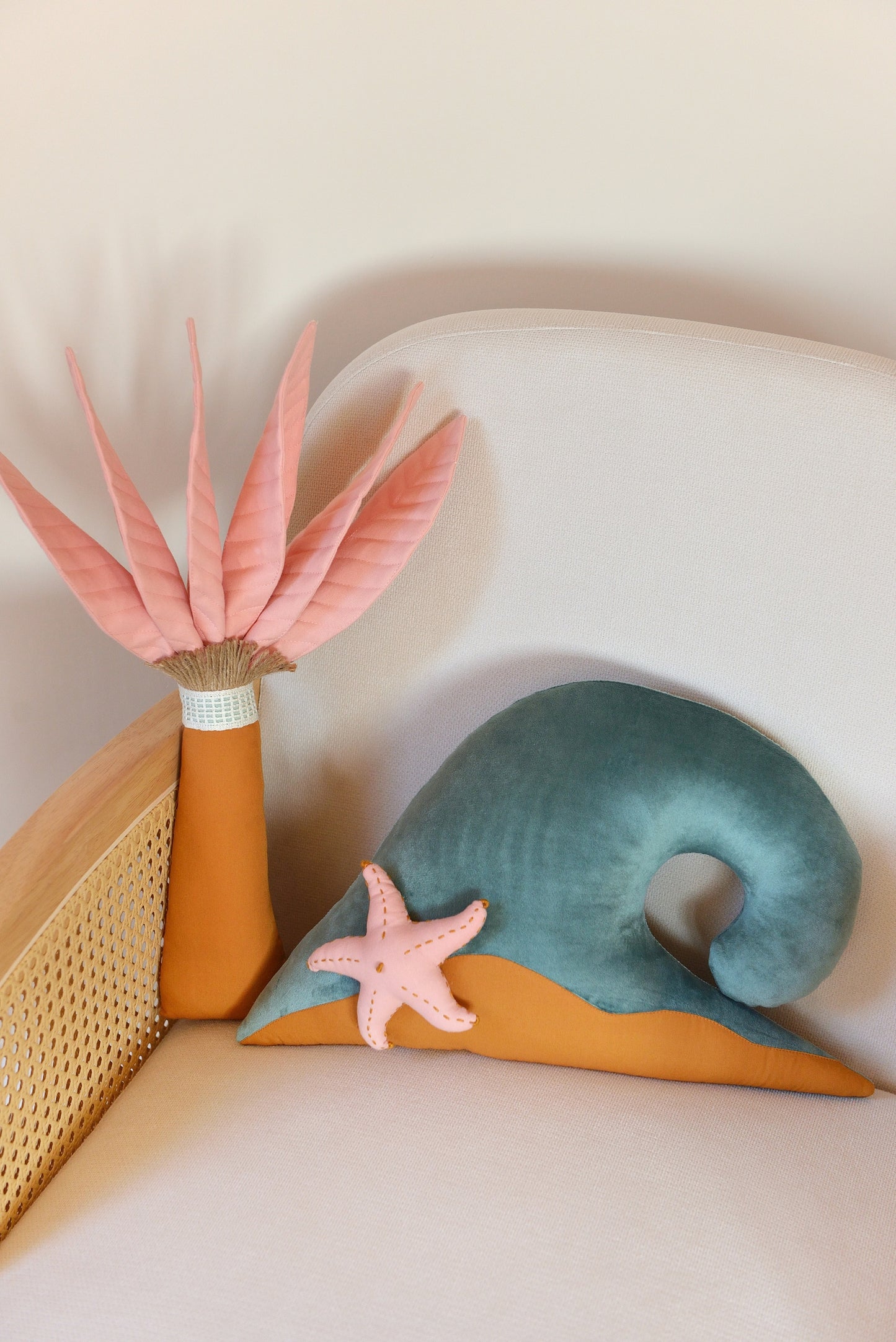Palm tree and ocean wave shaped decor pillow placed on an ivory armchair.