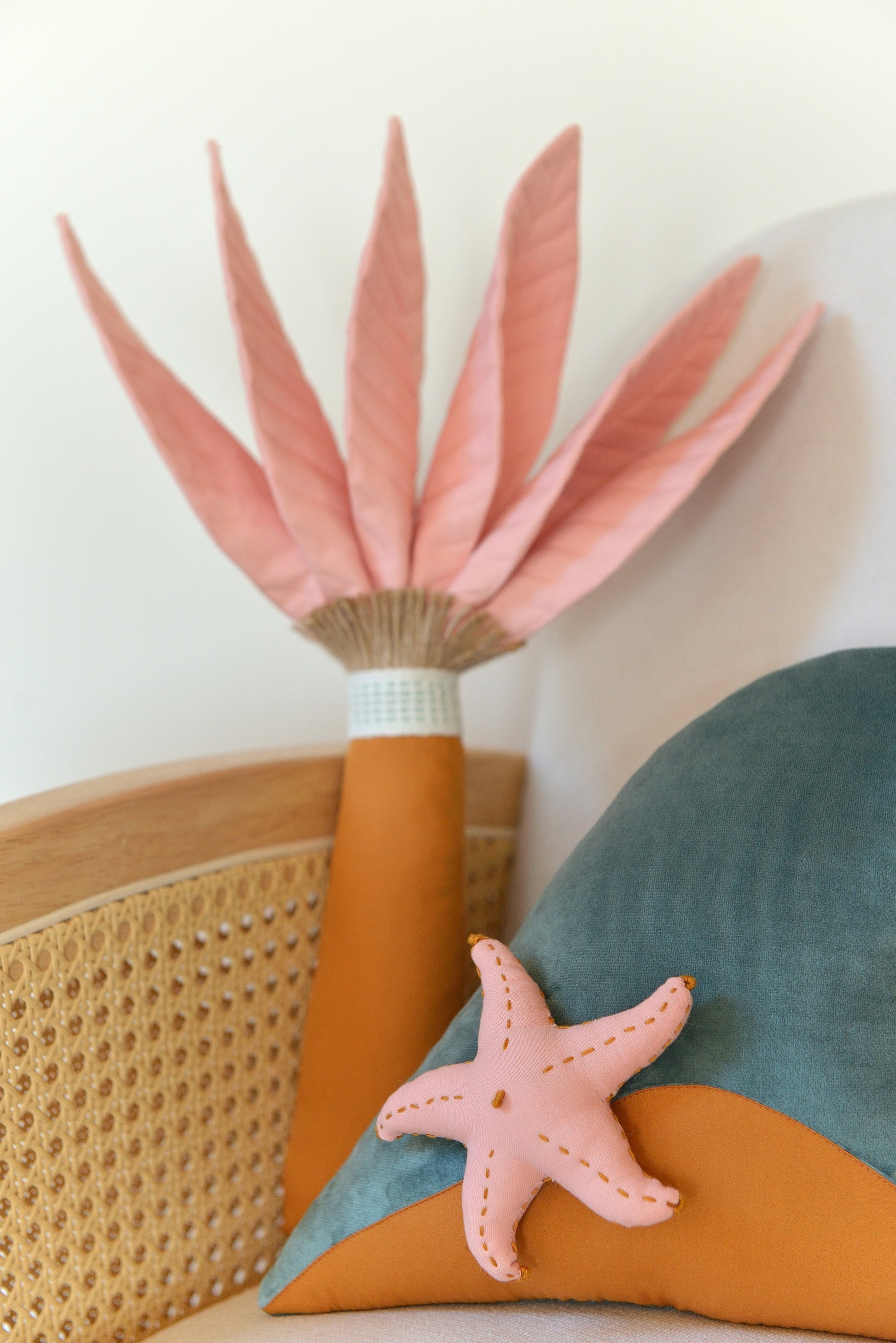 Closeup of palm tree and ocean wave shaped decor pillow placed on an ivory armchair.