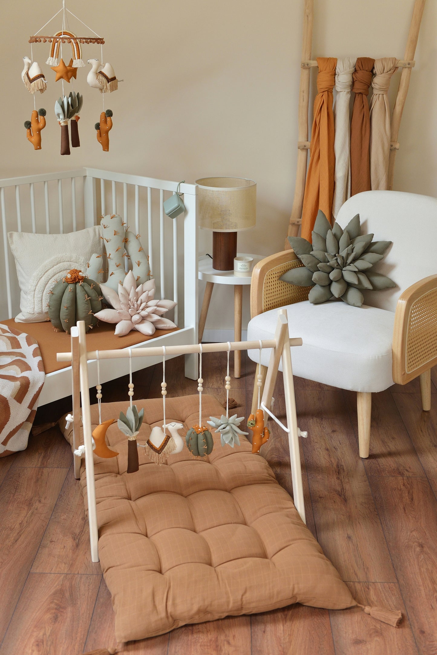 Desert themed baby room with white crib, rattan armchair and baby play gym with hanging toys in the foreground.