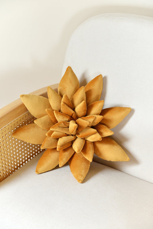 Standard size succulent shaped velvet decor pillow in golden yellow colour placed on an ivory rattan armchair.