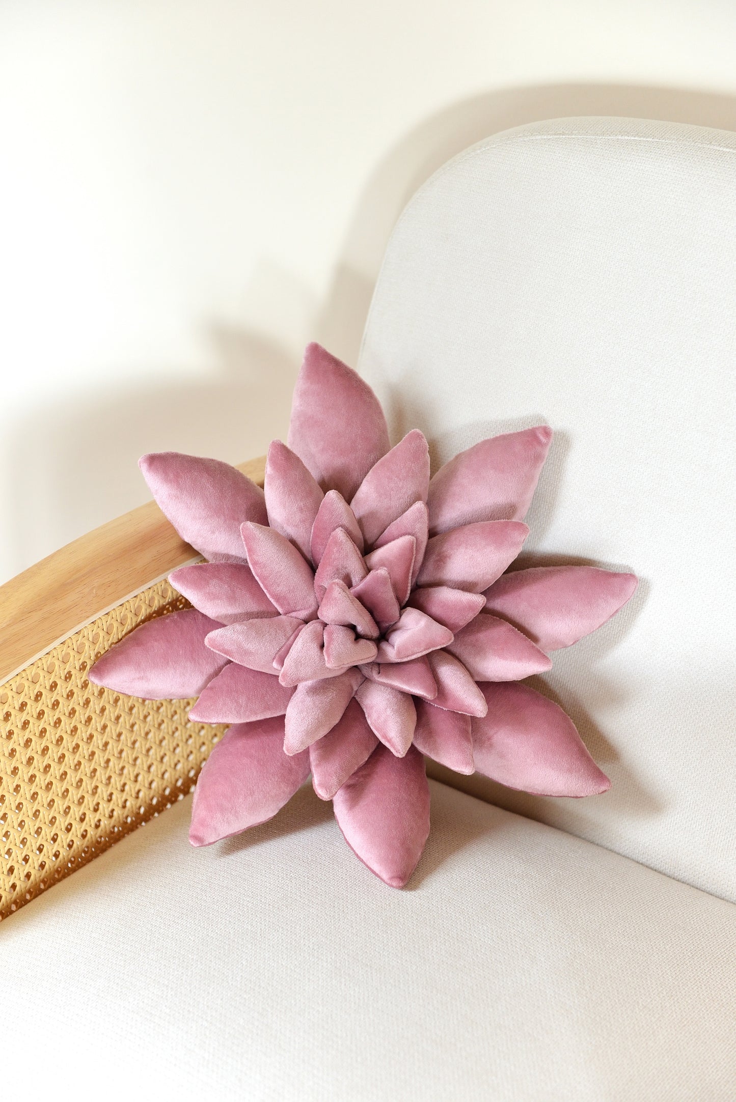 Standard size succulent shaped velvet decor pillow in lilac colour placed on an ivory rattan armchair.
