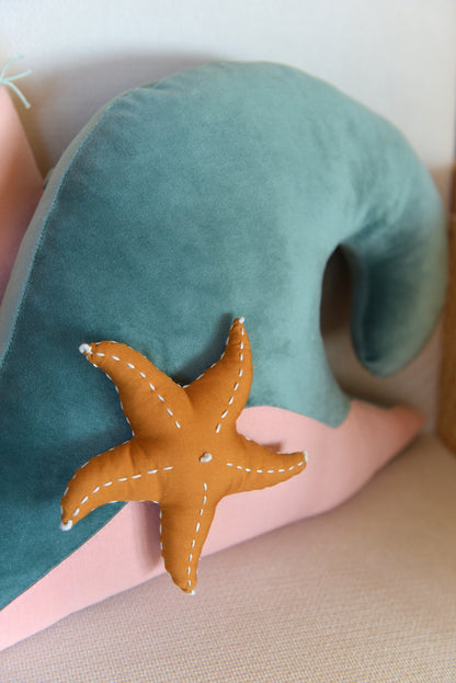 Closeup of ocean wave shaped decor pillow accented with a starfish.